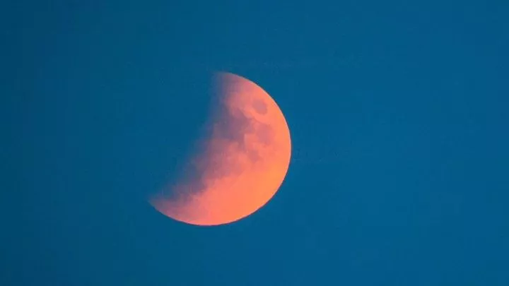 A partial lunar eclipse is visible over the sea in Sidmouth, Devon, in 2019. Pic: PA