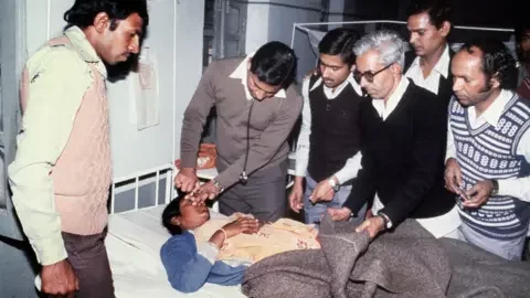 Getty Images A blinded victim of the Bhopal tragedy receives first aid from doctors at Bhopal's hospital on December 04, 1984 after a poison gas leak from the Union Carbide factory killed 20000 persons and injured around 300000. The tragedy occurred when a storage tank at a pesticide plant run by Union Carbide exploded and poured cyanide gas into the air, immediately killing more than 3,500 slum dwellers. (Photo by BEDI / AFP FILES / AFP) (Photo by BEDI/AFP FILES/AFP via Getty Images)<br />