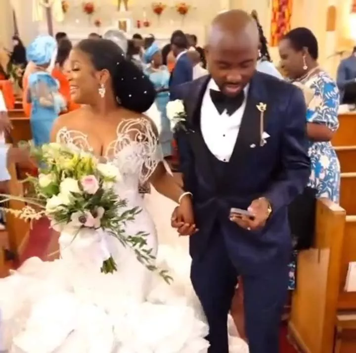 Nigerians react to trending video of groom checking his phone while walking down the aisle with his wife