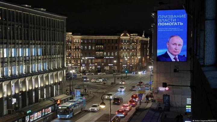 Cars drive along an avenue as a digital screen shows an image of Russian President Vladimir Putin on March 1, 2024