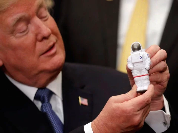 Donald Trump holds a figurine of an astronaut