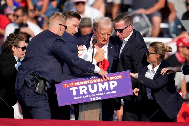 Donald Trump being helped off stage at a campaign event.