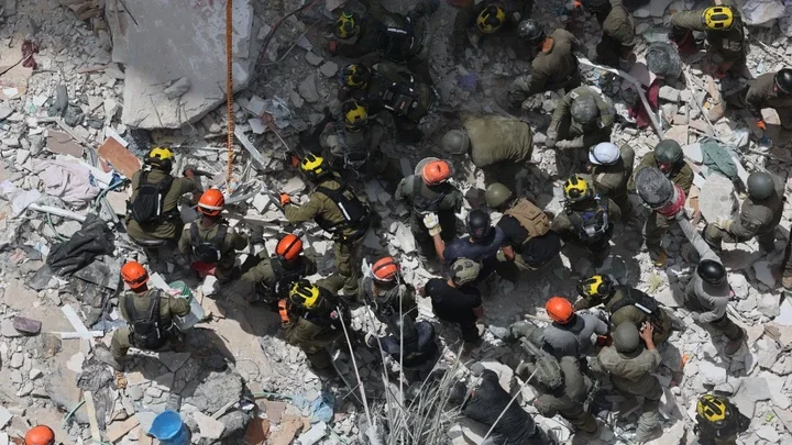 EPA Members of Israel's Home Front Command search for missing people under the rubble of a partially collapsed residential building