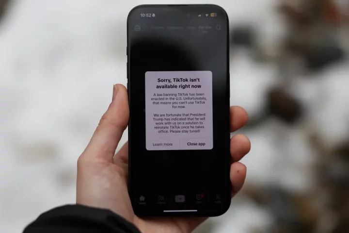 Illustration of a phone displaying a message that TikTok is unavailable in the U.S. due to a law banning it.