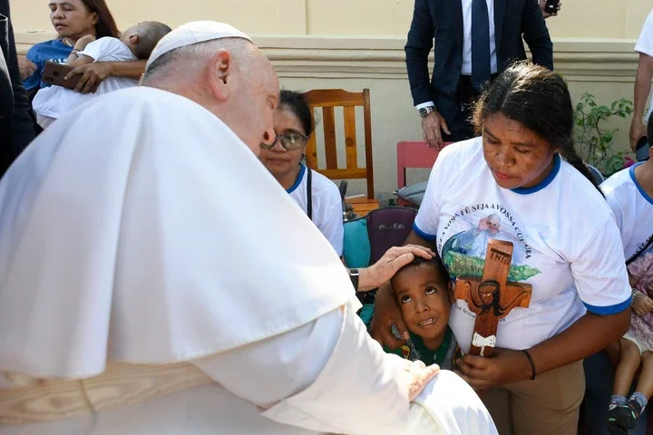 Pope Francis (L) blesses a child during a visit for children with disabilities at the Irmas Alma school in Dili.