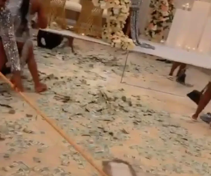 'Plenty dollars in Nigeria?' - Lady wows many, uses big broom to sweep $50, $100 bills sprayed at wedding party