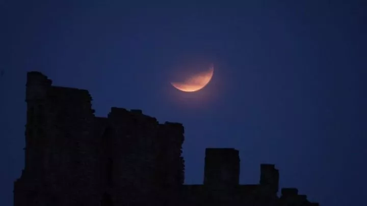 A partial lunar eclipse is visible above Tynemouth Priory in 2019. Pic: PA