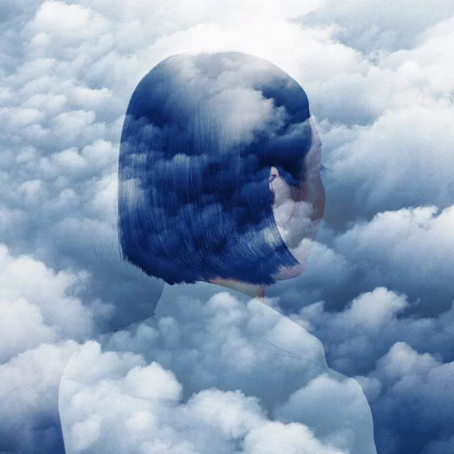 double exposure of woman looking in to clouds