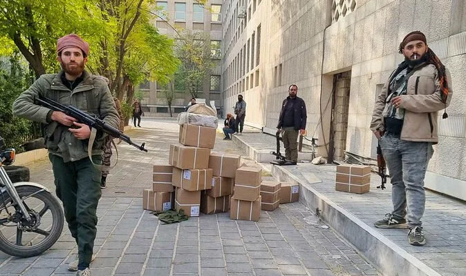 Chaos in Damascus as buildings set alight and people loot bags of money from central bank