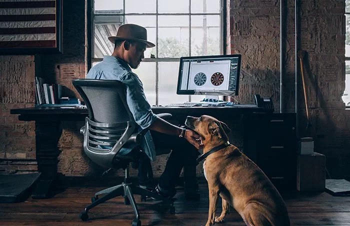 Man sitting near computer and petting dog.