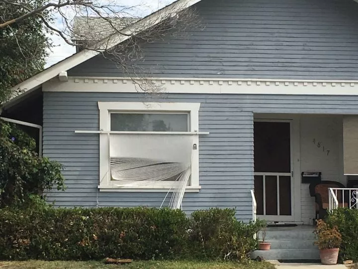 A house with a broken window blind meant for the interior hanging unevenly