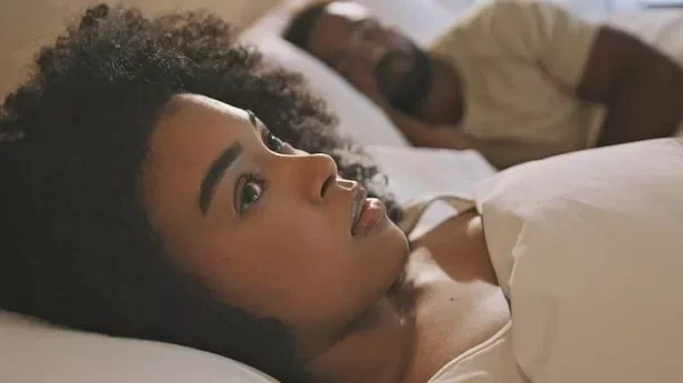 Worried female laying in bed with her husband looking anxious and concerned
