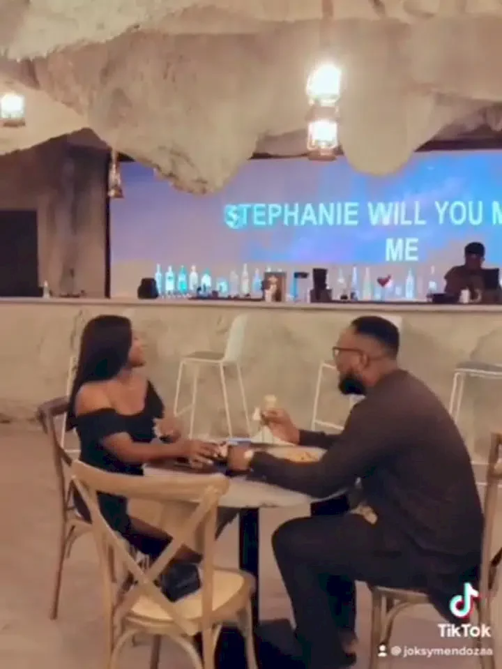 Reactions as man sits on chair to propose to girlfriend in restaurant (Video)