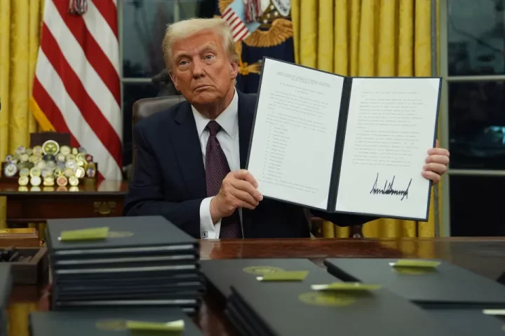 President Trump holding a signed executive order commuting sentences for January 6th offenses.