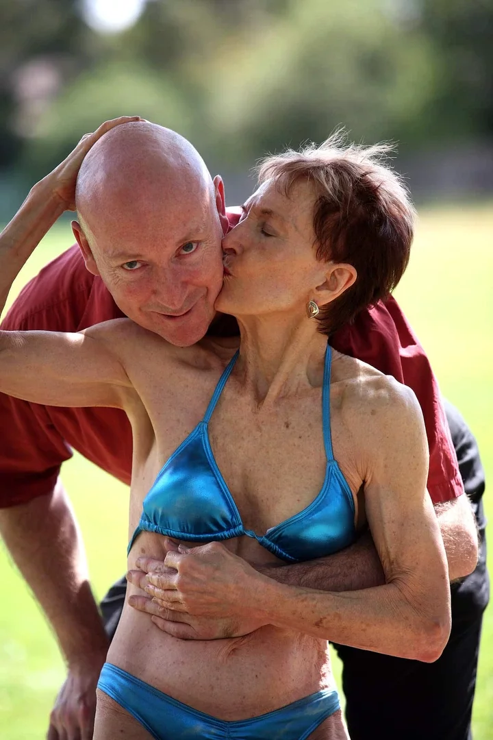 A mature-aged couple embrace, with the woman kissing the man on the cheek.