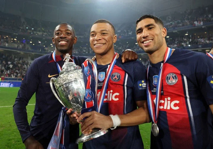 Soccer Football - Coupe de France - Final - Olympique Lyonnais v Paris St Germain - Stade Pierre-Mauroy, Villeneuve-d'Ascq, France - May 25, 2024 Paris St Germain's Kylian Mbappe, Achraf Hakimi, and Ousmane Dembele celebrate with the trophy after winning the Coupe de France REUTERS/Catherine Steenkeste