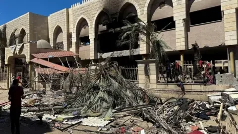 Reuters Palestinians look at damage at the site of an Israeli strike on a school sheltering displaced people, amid the Israel-Hamas conflict, in Gaza City August 10, 2024