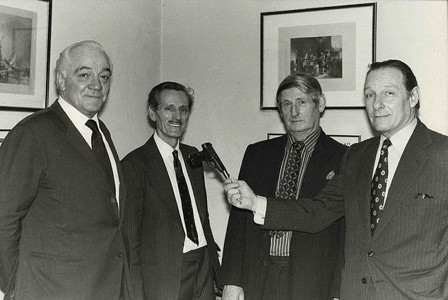 Corporal Charlie Hackney (second from left) seen with Major Charles 'Pat' Riley (left) as they reveal what they believed to be Adolf Hitler's suicide weapon, a Walther PP