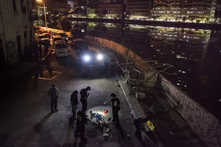 Police investigators inspect the body of John Estrella, 18, who was allegedly killed by unidentified assailants on June 26, 2017 in Manila, Philippines. As with thousands of others who died in connection with the government's campaign against drugs, the lifeless body of Estrella was allegedly found by policemen in a dark street with a pistol and sachets of illegal drugs in his body.