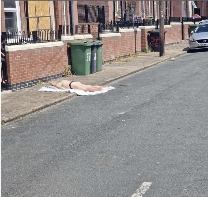 A person sunbathing on a sidewalk