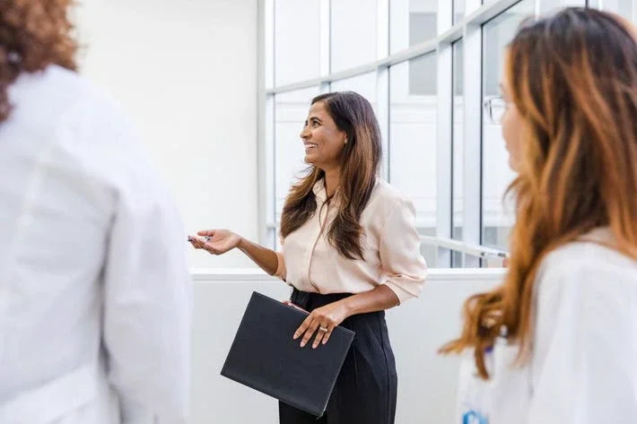 Businesswoman smiles and talks with the unrecognizable healthcare professionals