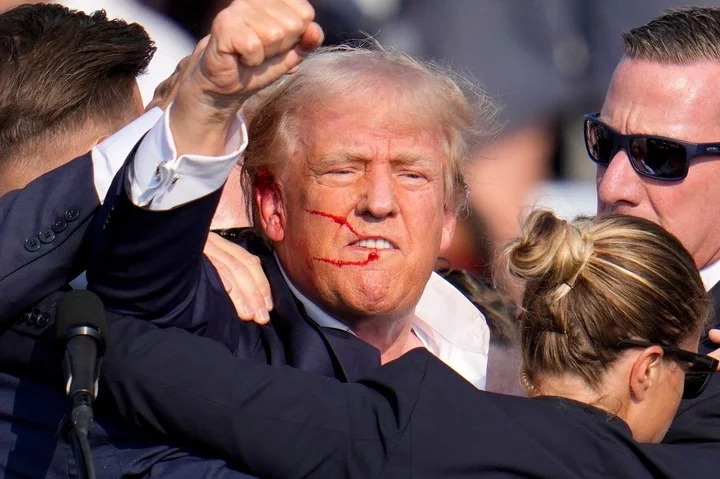 Donald Trump with a bloody face after an assassination attempt.