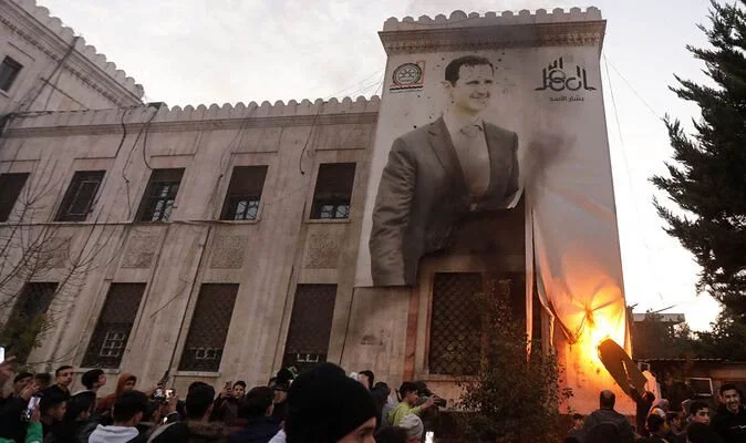 Chaos in Damascus as buildings set alight and people loot bags of money from central bank