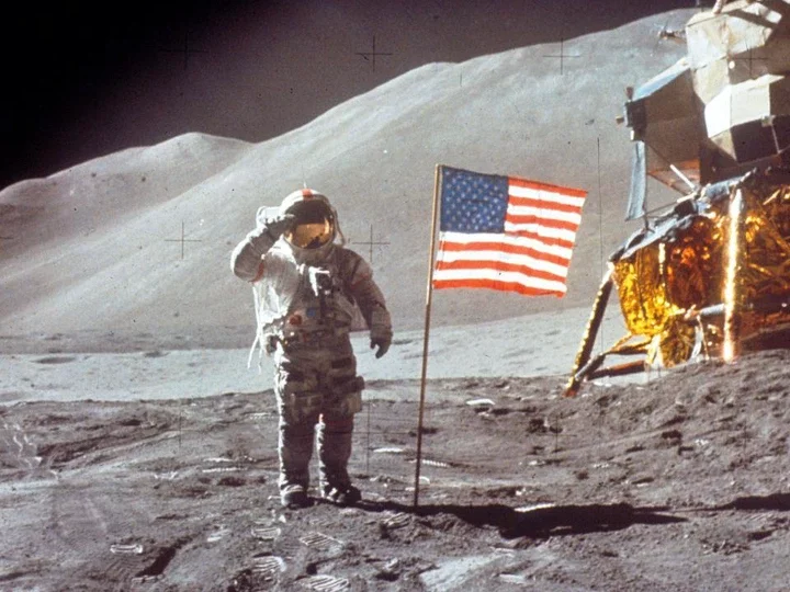 An astronaut on the moon near an American flag