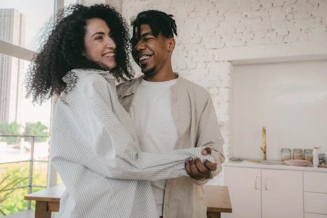 Happy couple dancing together and laughing outdoors, showing emotional connection and playfulness in a healthy relationship