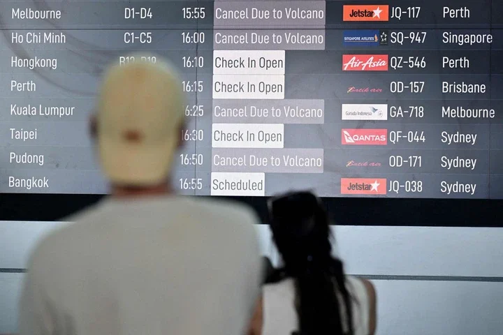 Passengers look at an electronic board displaying cancelled flights after the nearby Mount Lewotobi Laki-Laki volcano erupted, at Ngurah Rai International Airport in Tuban near Denpasar, on Indonesia's resort island of Bali on June 18, 2025. Dozens of flights to and from Indonesia's resort island of Bali were cancelled on June 18, authorities said, after a volcano in the archipelago's east erupted, shooting an ash tower 10 kilometres (six miles) into the sky. (Photo by SONNY TUMBELAKA / AFP)