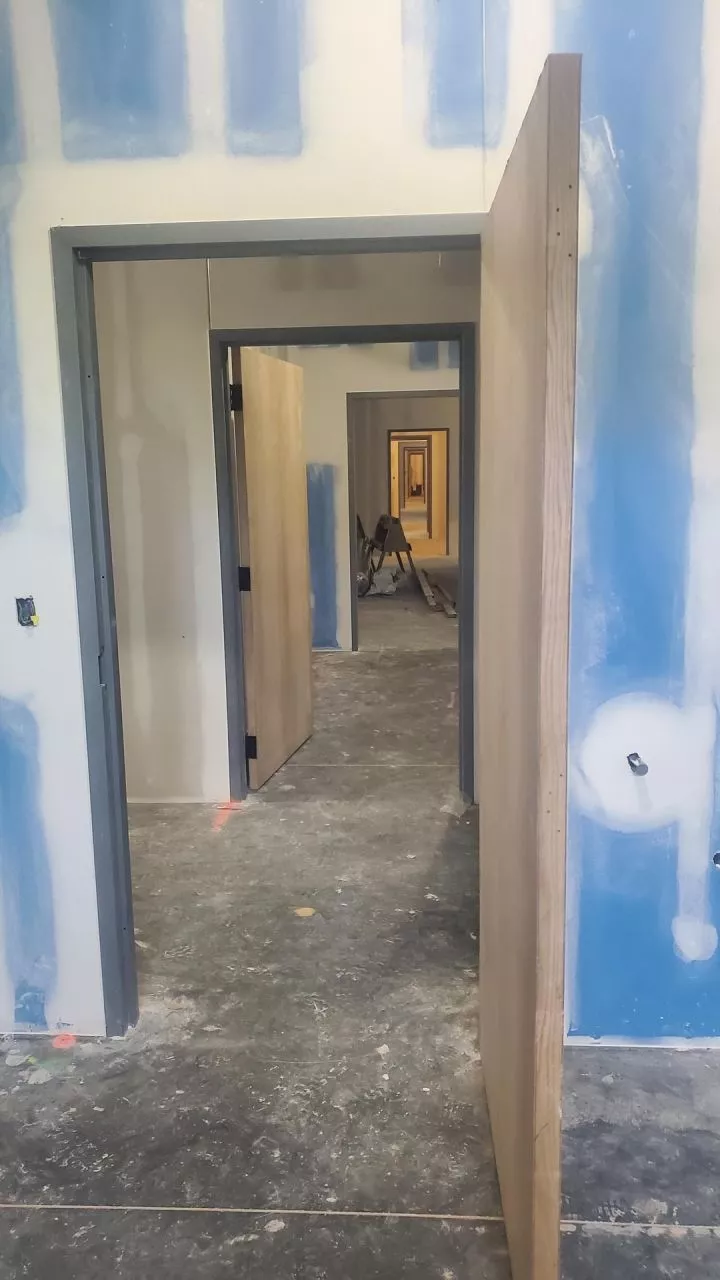 Partially constructed hallway with several unfinished doorways and open doors that all line up