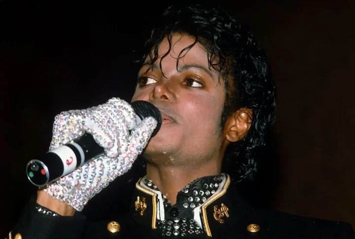 Michael Jackson wears a sequined glove and holding a microphone.