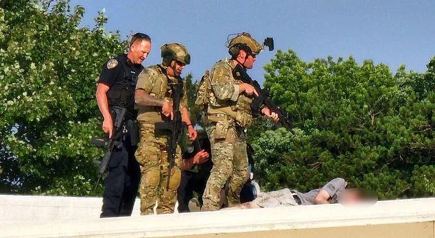 Police personnel stand over the body of Thomas Matthews Crooks on a rooftop near the Trump rally on Saturday