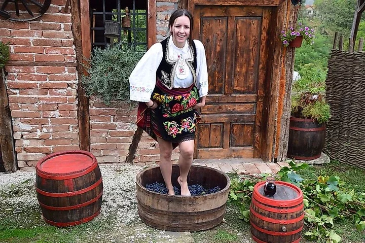 A women preparing grapes in Serbia, wearing a traditional outfit. Image Credit Miki Veskovic via Wikimedia.