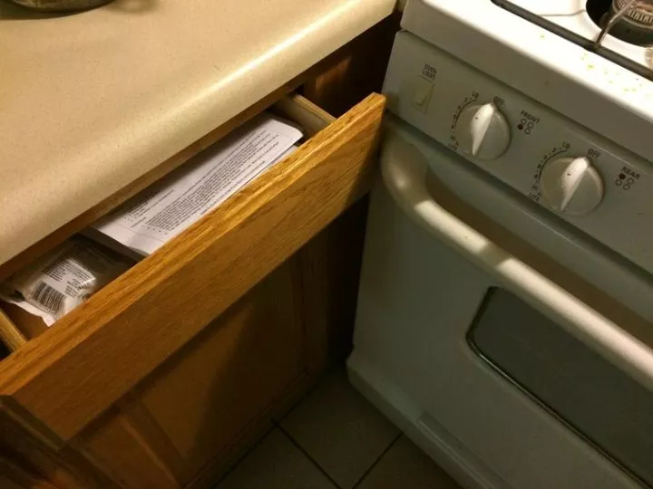 Kitchen drawer slightly open, blocked from opening further by oven handle