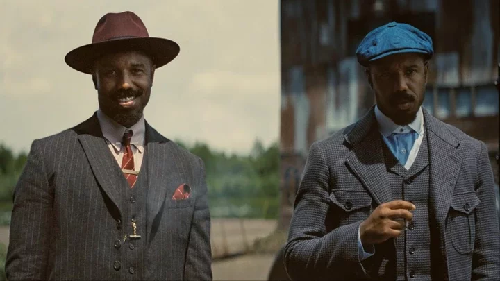 Two men smirk while standing next to each other.