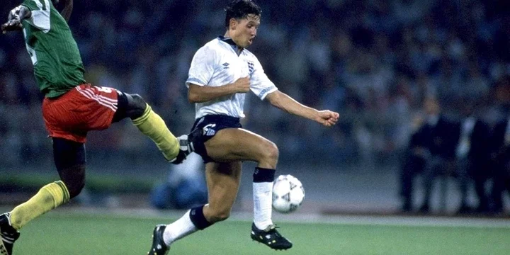 Gary Lineker battles for the ball with a Cameroon player.