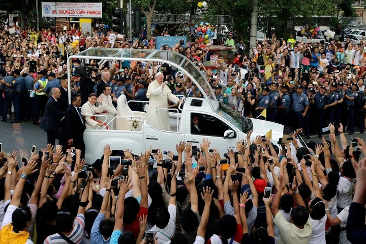 Pope Francis waves to onlookers from his popemobile as his motorcade passes by on the way to another 'Meeting With Families