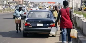 Black market fuel vendors tries to sell fuel to a motorist on Lagos-Ikorodu highway 17 June 2007. [Getty Images]