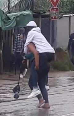 'The guy fit be last born' - Reactions as lady backs her man to cross flooded road (Video)