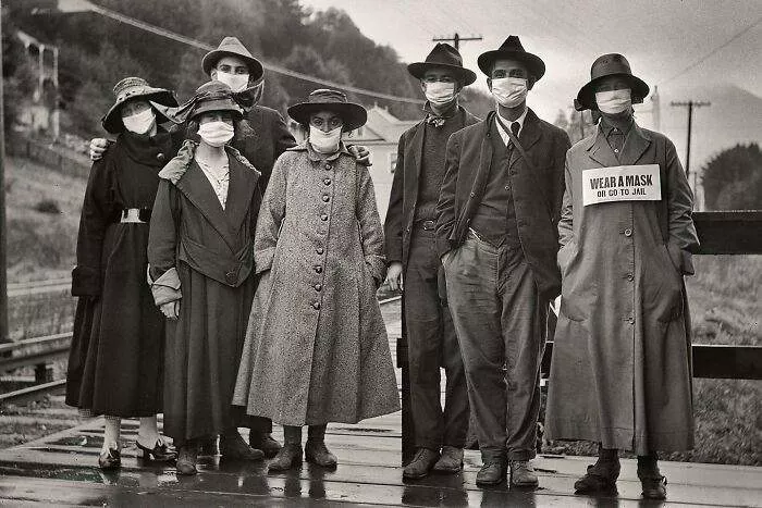 Rail Commuters Wearing White Protective Masks, One With The Additional Message 'Wear A Mask Or Go To Jail,