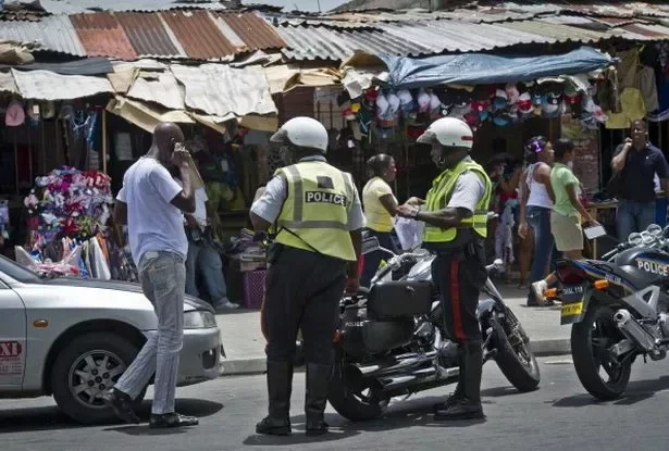 Jamaican policemen talk to a driver on a shopping street in downtown Kingston