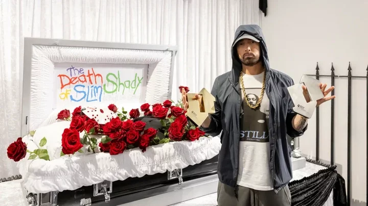 The Official Charts Company  Eminem standing in front of a white coffin, holding two charts awards 