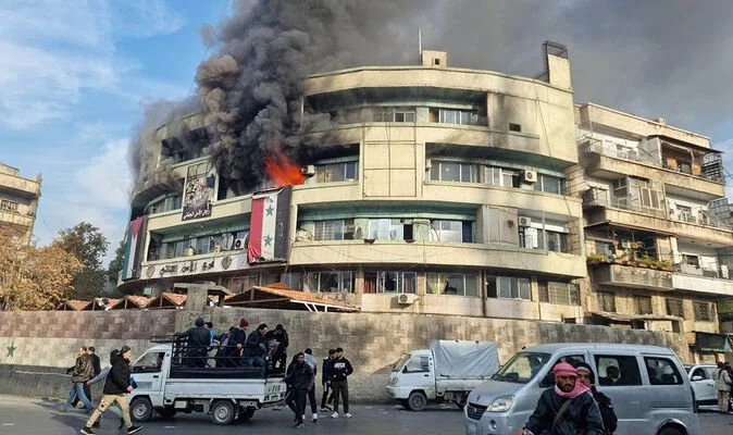 Chaos in Damascus as buildings set alight and people loot bags of money from central bank