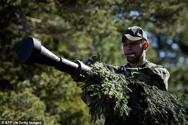 A soldier of the P18 Gotland Regiment of the Swedish Army camouflages an armoured vehicle during a field exercise near Visby on the Swedish island of Gotland