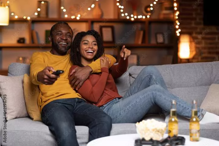 Joyful african american couple watching TV together at home Stock Photo - Adobe Stock