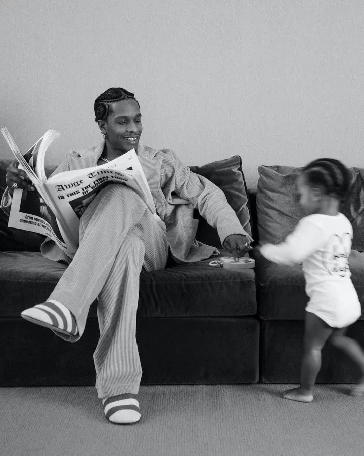 a person and a girl sitting on a couch reading a newspaper