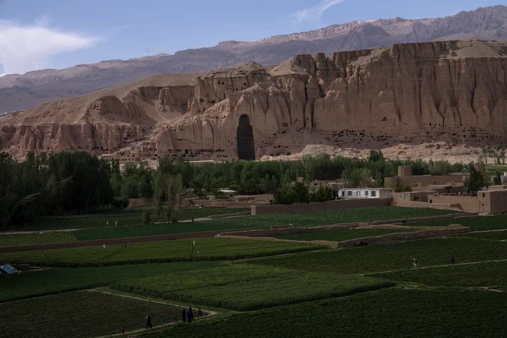 Villagers walk in the fields near the niche of the giant Buddha statue destroyed by the Taliban in 2001, in Bamiyan, Afghanistan, Saturday, June 17, 2023. (AP Photo/Rodrigo Abd,File
