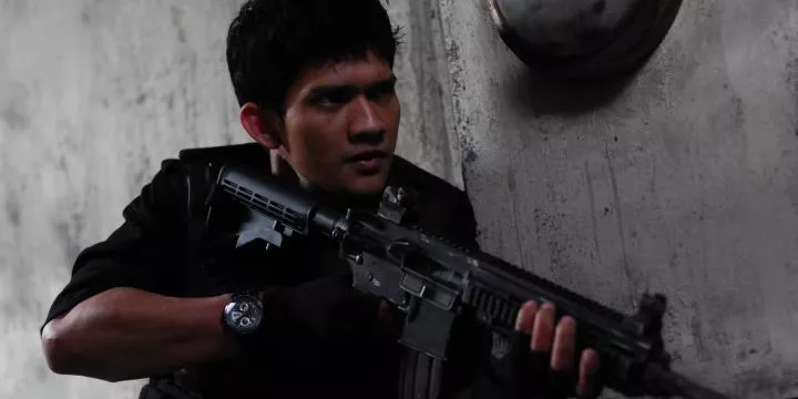 A rookie for a S.W.A.T. team takes cover behind a wall while holding a machine gun.