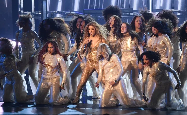 Shakira performing on stage with backup dancers.